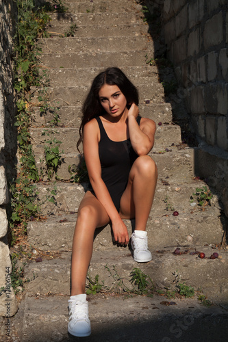 beautiful sport girl in black body sits on the stairs