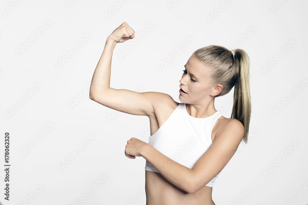 Foto de Junge Blonde Frau im Top zeigt ihre Muskeln im Oberarm und ...