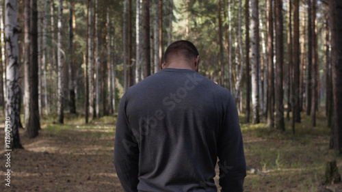 Rear view of fit young man with muscular build standing against sport ground background. Fighter looking at copy space. The muscular male back