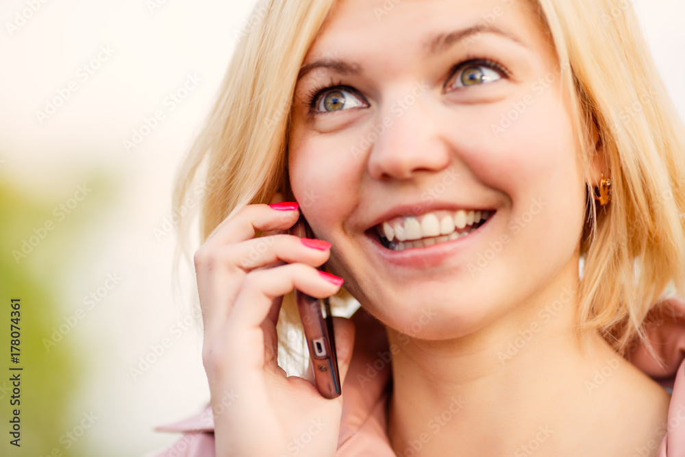 Woman talking on the phone and smilling in the park Woman talking on the phone and smilling in the park