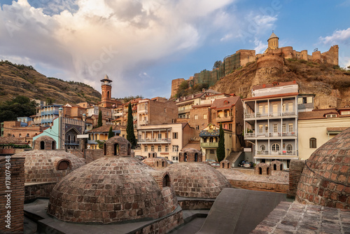 Sulfur baths in the Abanotubani district of Tbilisi. Georgian houses against the background of the fortress Narikala. City landscape at sunrise.