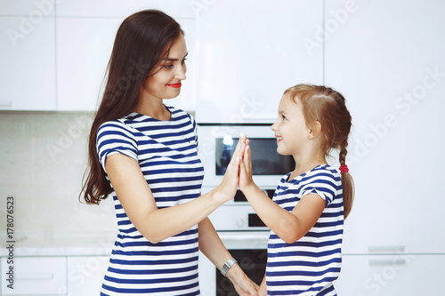 Smiling mother and daughter on a beautiful white kitchen dough blender knead