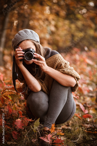young woman taking pictures  in autumn forest