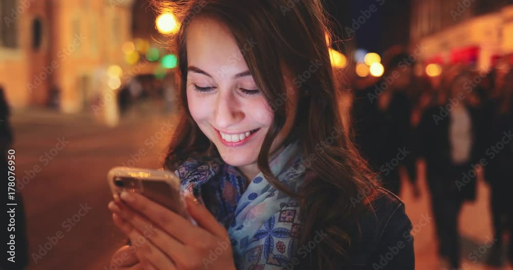 Woman Using Smart Phone at Night in the City. SLOW MOTION 4K DCi. Attractive young woman texting, talking on smartphone outdoors. Blurred Night Busy Street lights background. Woman Using Smart Phone at Night in the City. SLOW MOTION 4K DCi. Attractive young woman texting, talking on smartphone outdoors. Blurred Night Busy Street lights background.