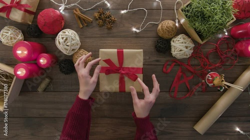 Top view hands unwrapping christmas presents at wooden desk from above with christmass decoration