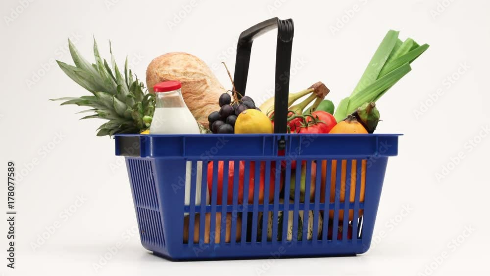 Supermarket shopping basket filled with groceries moving on white background.