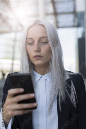 Young businesswoman checking cell phone in the city