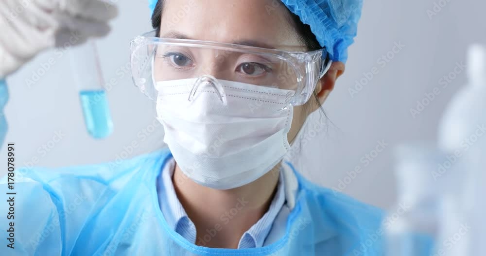 Female doctor analyzing liquid in test tube. Female doctor analyzing liquid in test tube.