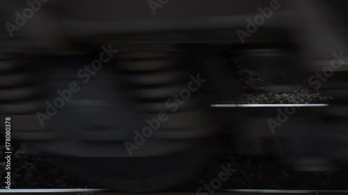 Rail tracks and train passing by on high speed, view to the wheels