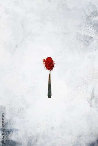 Ground chili pepper in a silver spoon, spice background, top view