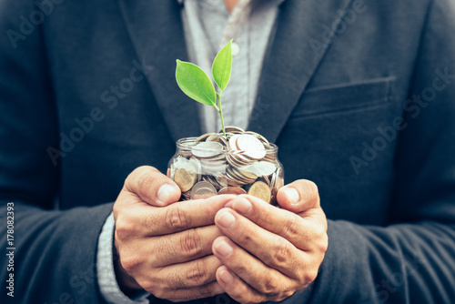 Businessman cover growing plant with coin money,Plant growing out of coins with filter effect retro vintage style,concept money growing and small tree in jar, economy concept