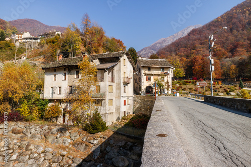 Piedicavallo, Italy - October 20, 2017: Rustic alpine houses and bridge in the village of Piedicavallo with a beautiful autumn scenery
