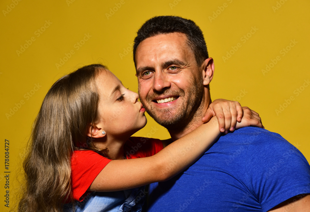 Daughter kisses her daddy in cheek. Child and father hug Daughter kisses her daddy in cheek. Child and father hug
