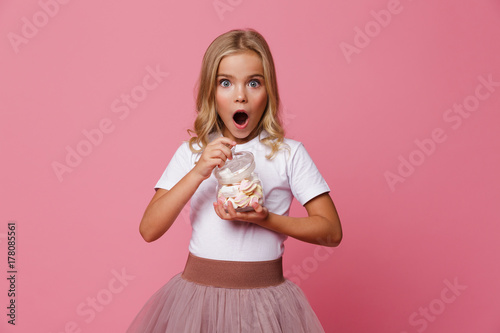 Portrait of an excited little girl holding jar of marshmallow