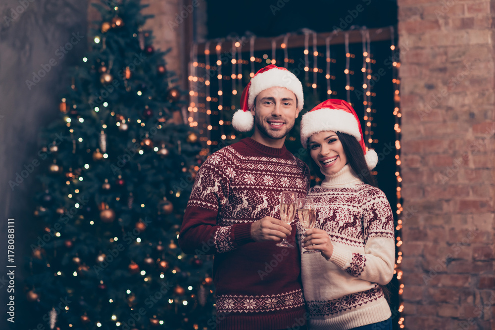 Festive friends with stemware of martini embrace bonding, so excited in knitted cute traditional x mas costumes with ornament, headwear, jeans, enjoy, december time, firtree, garland, night