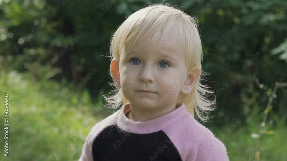 Portrait of little female beautiful kid watches in the park. Slowly Portrait of little female beautiful kid watches in the park. Slowly