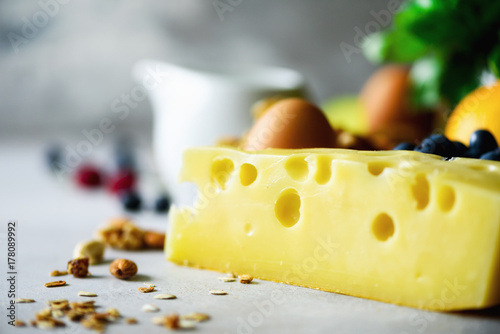 Cheese for braekfast, macro, milk, nuts, eggs, basil on grey concrete background. photo