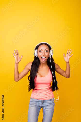 Omg! Stylish astonished afro lady dj with bronze skin, so fit and slim, hot, enjoying to the stereo sound in big modern ear phones, sing, yell, shout, dance, laugh, funky summer holiday mode