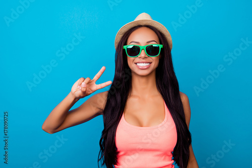 Attractive, excited carefree gorgeous traveller in trendy shiny specs, in singlet, so hot, fit and slim, relax, rest, chill mode! Showing peace gesture with fingers of her arm, long dark hair