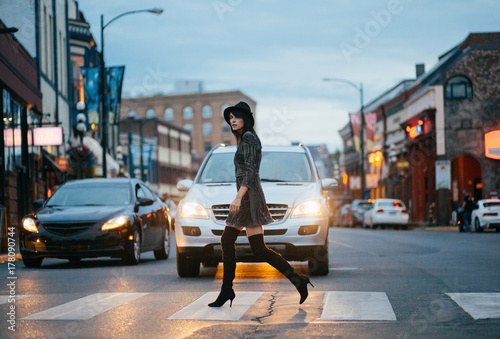 A stylish woman walking on a crosswalk at dusk
