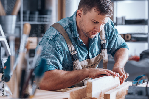 Carpenter sanding a wooden plank