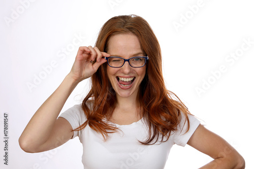 Hübsche rothaarige Frau mit Brille lacht und zwinkert