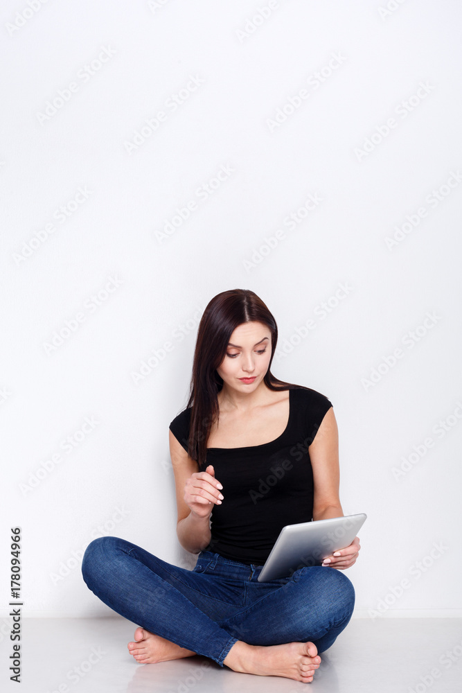 Woman using tablet, sitting on home floor