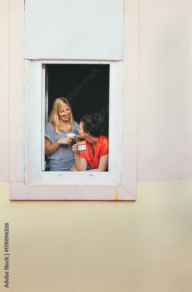 Two girls chatting at the window Two girls chatting at the window