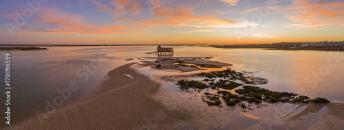 Aerial sunset and historic life-guard building at Fuseta fishing town, in Ria Formosa wetlands nature conservation park, Algarve. Portugal