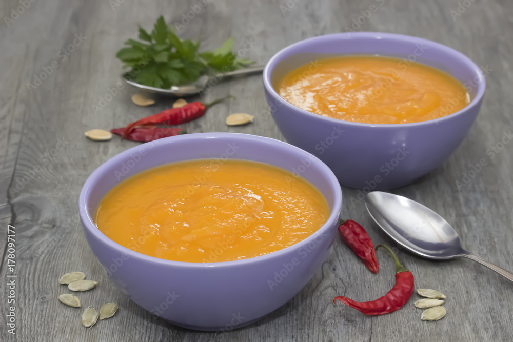 A bright cream soup of pumpkin on a gray wooden table. A bright cream soup of pumpkin on a gray wooden table.