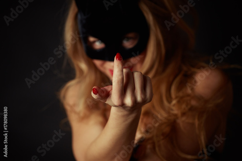 Fotografi A beautiful woman with a mask on her face makes a beckoning gesture with her finger