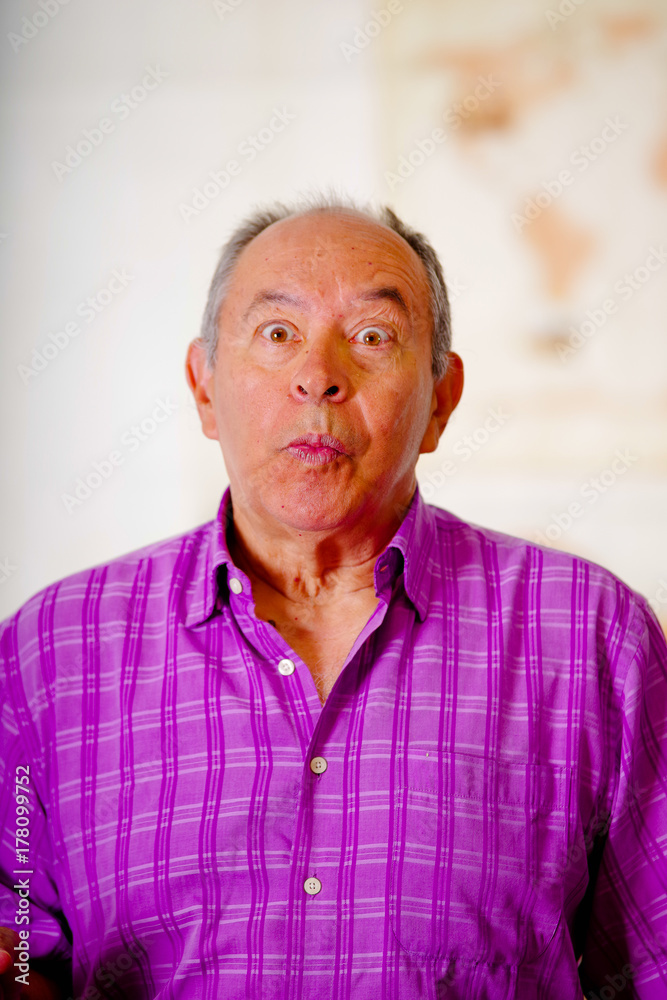 Portrait of a suprissed old man, doing a funny face and wearing a purple  square t-shirt in a blurred background Stock Photo | Adobe Stock