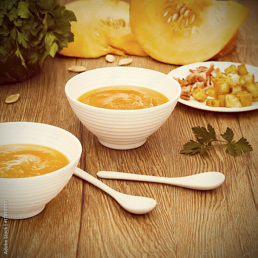 A bright cream soup of pumpkin on a wooden background. A bright cream soup of pumpkin on a wooden background.