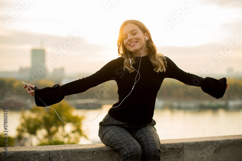 Trendy young woman listening music from smartphone outdoor