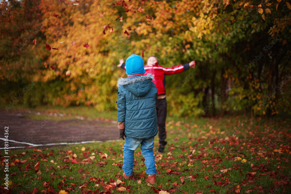 children playing with leaves in autumn park children playing with leaves in autumn park