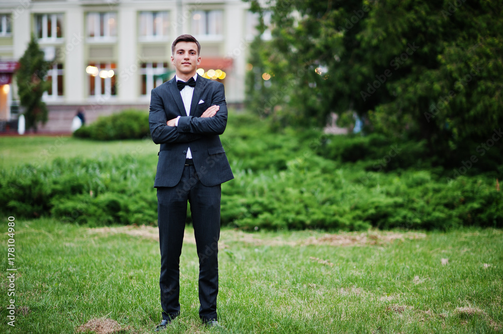 Portrait of a handsome young guy dressed in cool suit posing on the lawn on his prom day. Portrait of a handsome young guy dressed in cool suit posing on the lawn on his prom day.