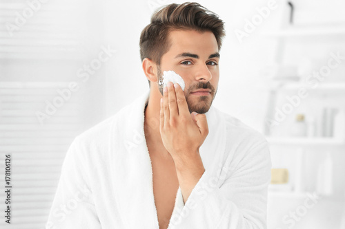 Young man applying facial c...