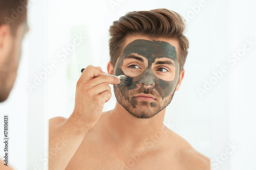 Young man applying cosmetic...