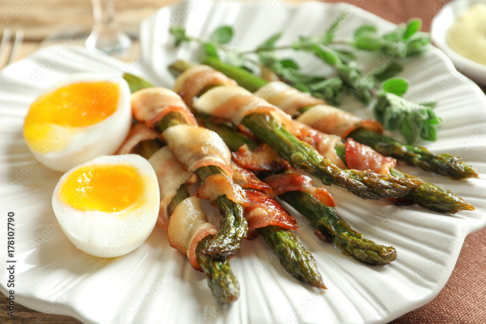 Plate with bacon wrapped asparagus on table, closeup