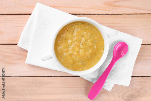 Bowl with creamy baby vegetable soup on wooden table