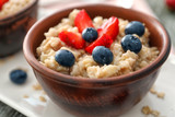 Tasty oatmeal with berries in bowl, close up