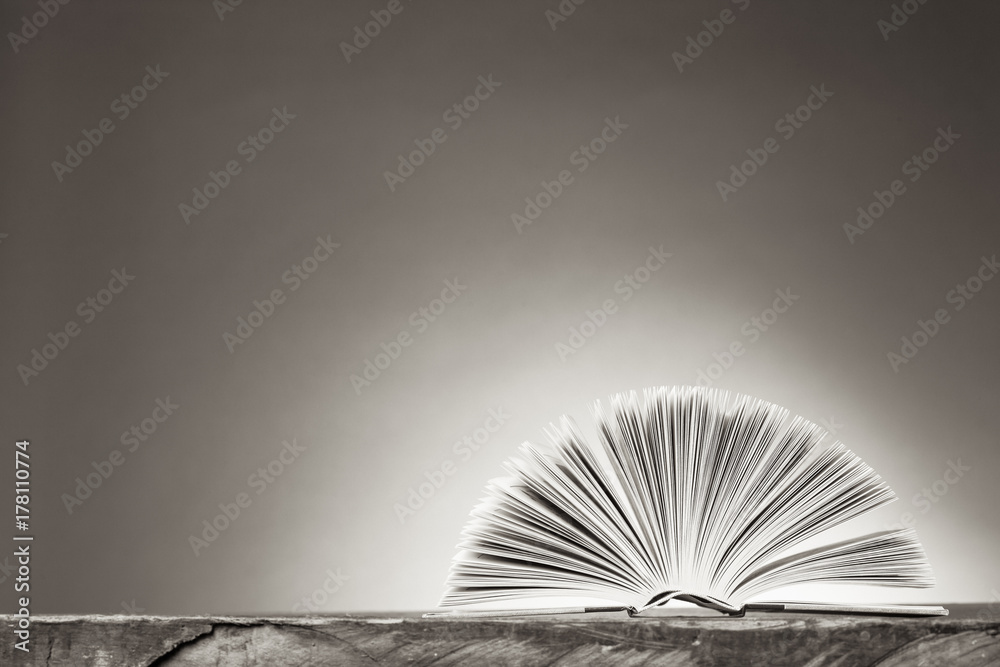 Open Book forming a fan on a wooden Table