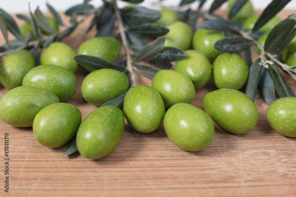 Harvested fresh olives with young olive twigs on wooden background Harvested fresh olives with young olive twigs on wooden background