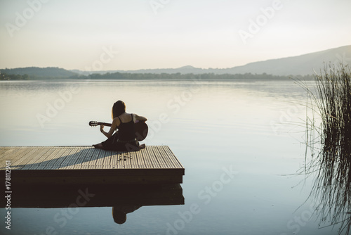 Young and free woman relaxing in the nature with a guitar