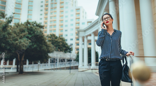 Businesswoman walking outdoors using mobile phone