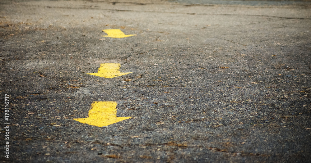 Close-up of directional yellow arrows painted on paved road with copy space for text. Path. Close-up of directional yellow arrows painted on paved road with copy space for text. Path.