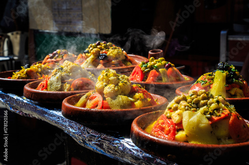 A lot of warm tagines with delicious vegetables on a market photo
