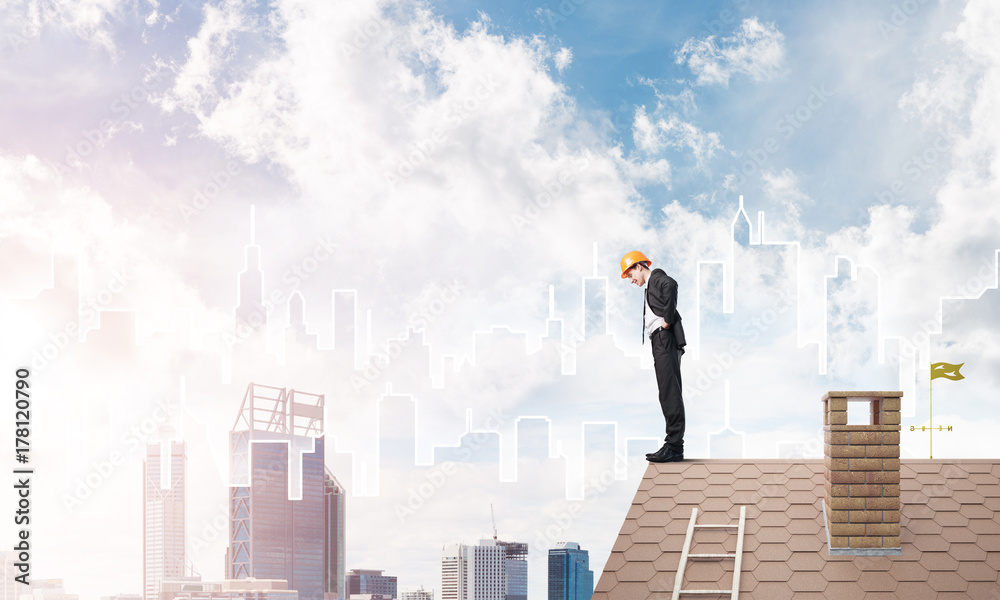 Engineer man standing on roof and looking down. Mixed media Engineer man standing on roof and looking down. Mixed media