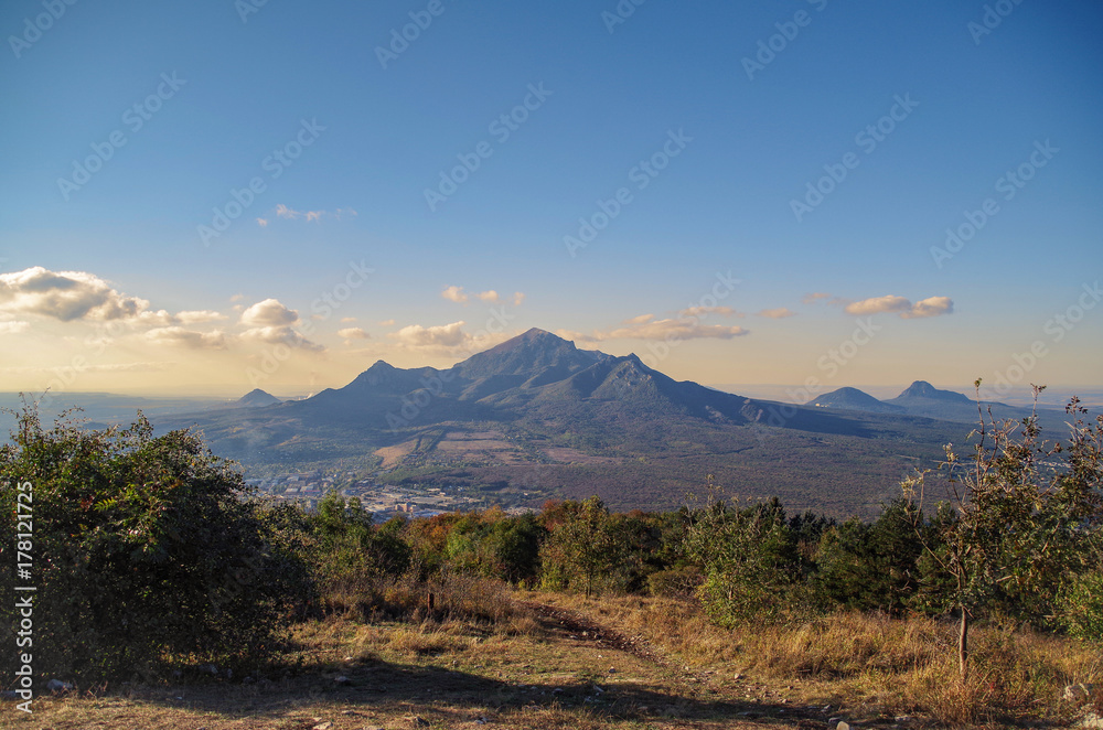 Scenic autumn view of Beshtau on a background of sunset sky. Beshtau is an isolated five-domed igneous mountain near Pyatigorsk in the Northern Caucasus. View from Mount Mashuk. Russia, Stavropol Krai