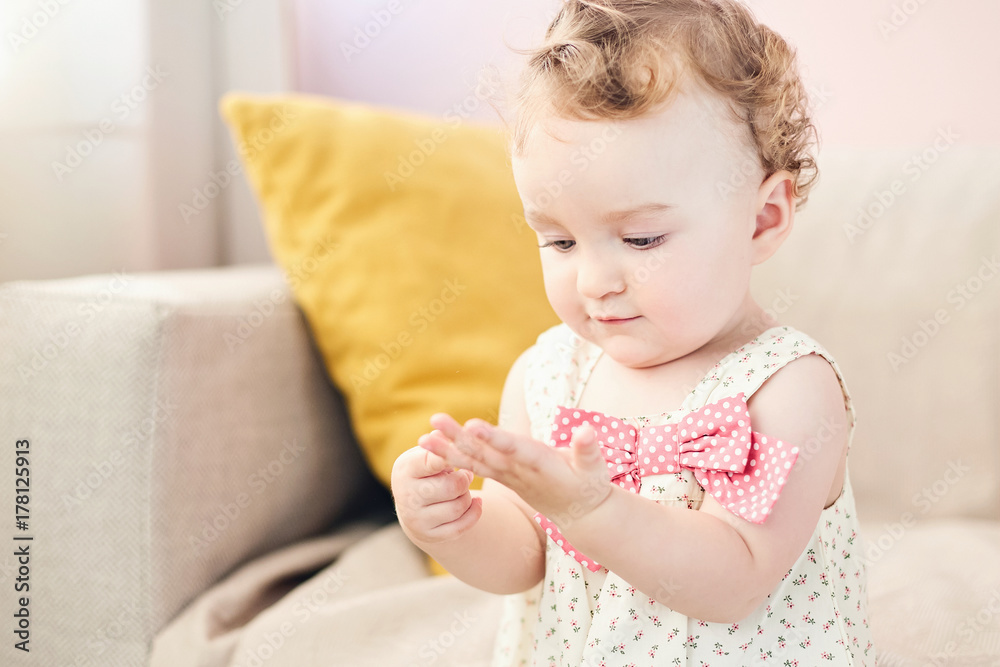 A happy baby in a pink, leans forward with a big smile. She is sitting in a portrait studio A happy baby in a pink, leans forward with a big smile. She is sitting in a portrait studio